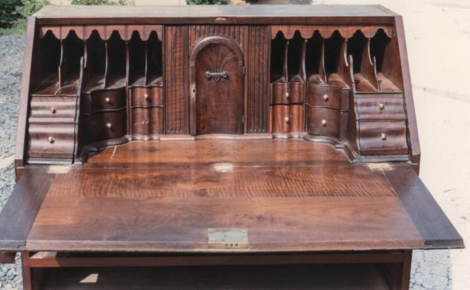 The desk interior behind the fall front is one complicated with no surfaces or drawer fronts left unshaped.